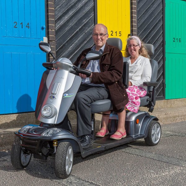 Scooterpac Tandem mobility scooter with elderly couple seated, showing dual seating and front three-quarter view