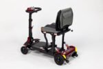Monarch Genie lightweight folding travel scooter three-quarter view showing red and black design with adjustable seat