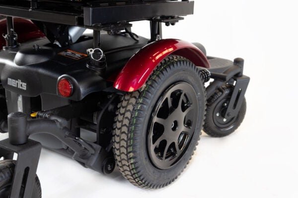 Merits Monarch Super Powerchair rear wheel detail view showing red fender and black treaded tire