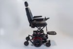 Monarch Super Powerchair side profile view showing black leather seat, red wheel accents, and sturdy six-wheel base